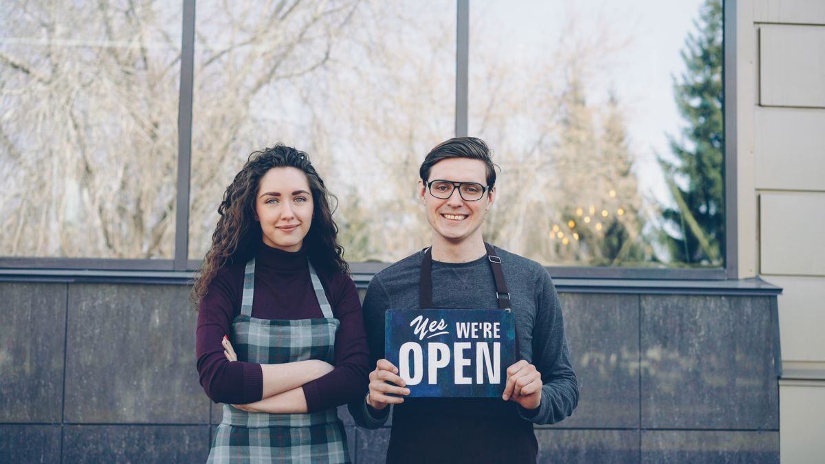 Two small business owners holding an open sign