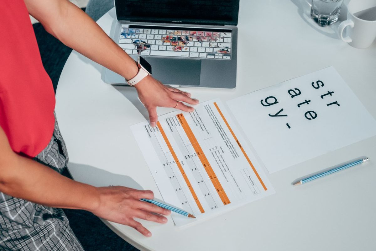 Two people reviewing a document beside a laptop
